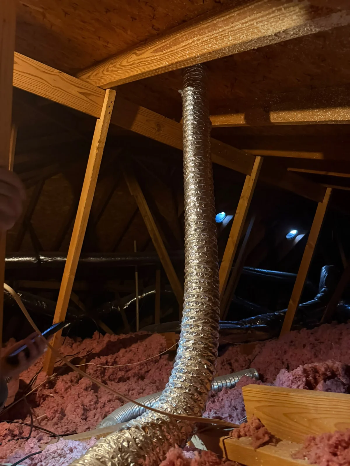Client photograph of a flexible vent pipe running through an attic
