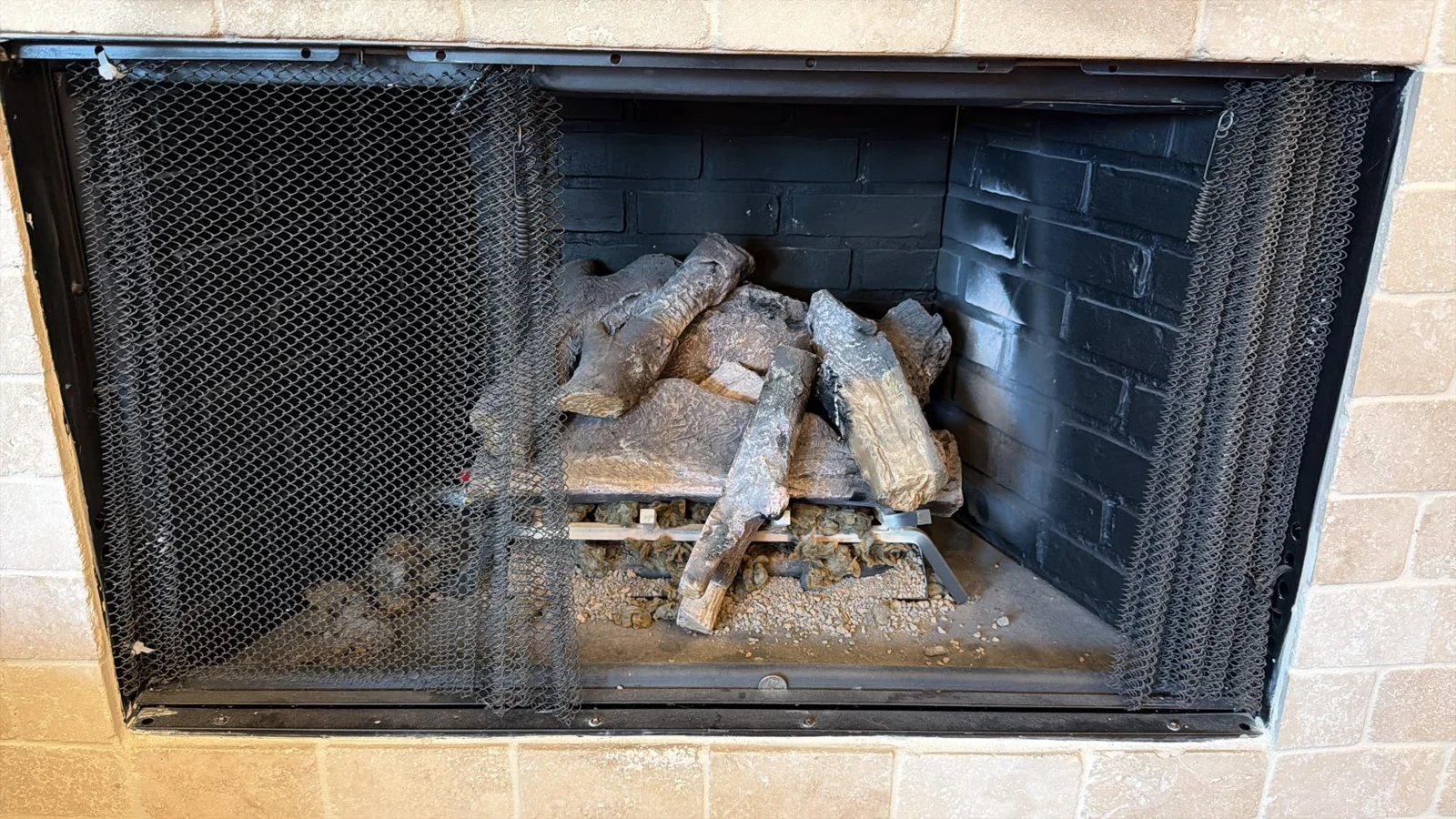 Client photograph of the earlier fireplace log arrangement behind a mesh screen