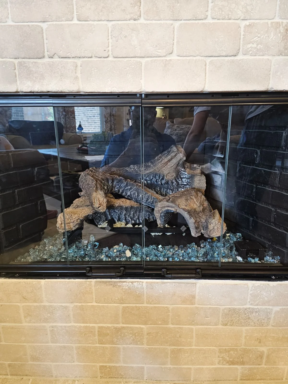 Client photograph of the matching brick fireplace with glass doors and a changed log arrangement