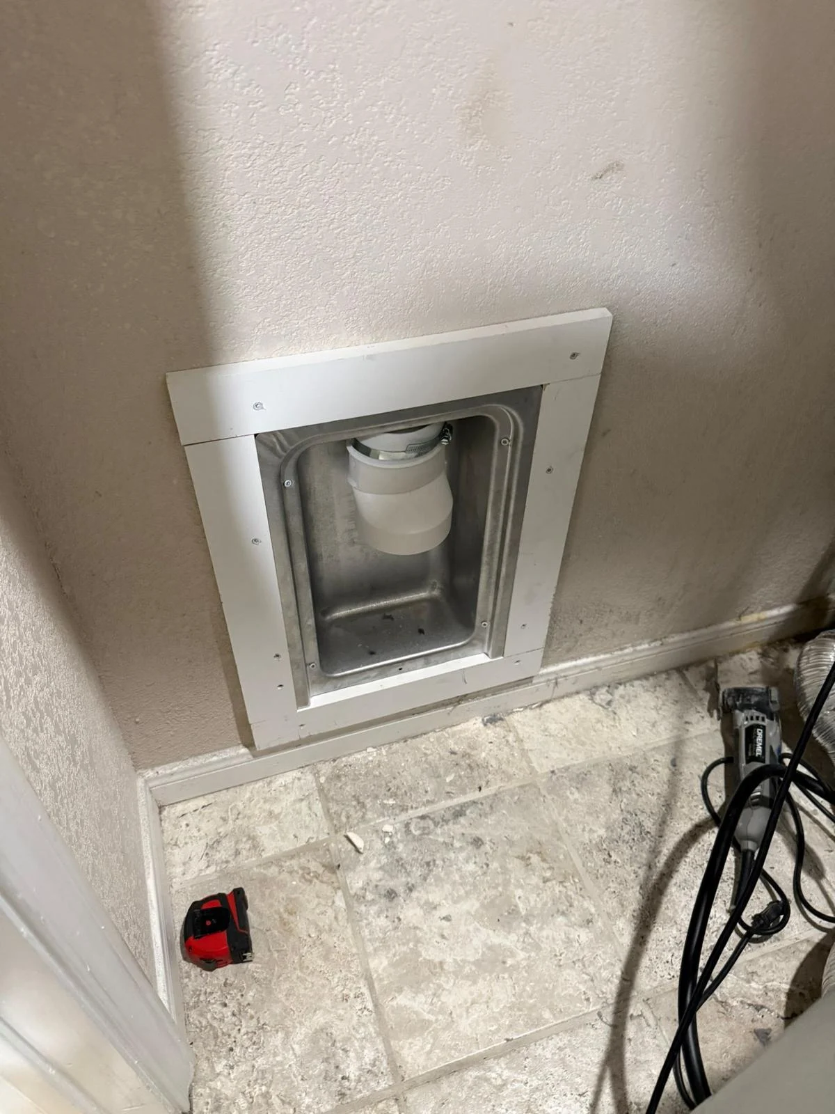 Client photograph of the matching tiled laundry area with a recessed dryer connection box