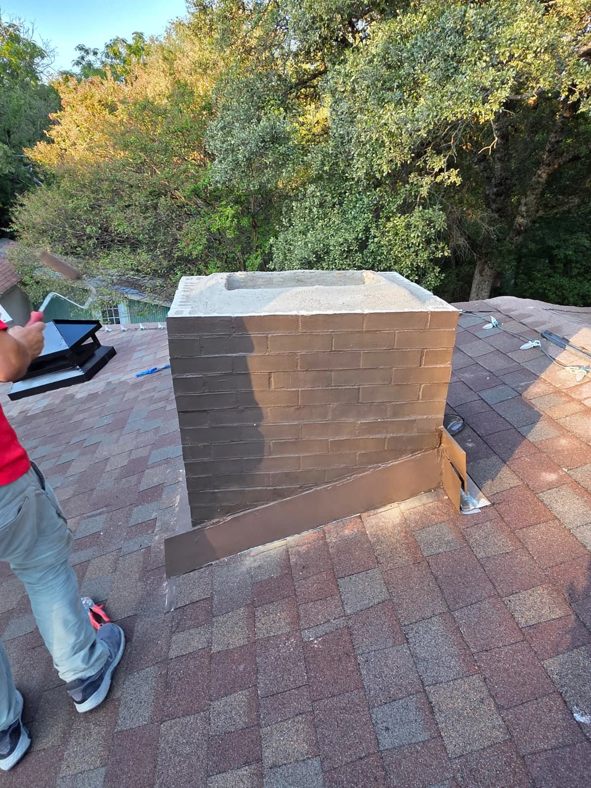 Client-supplied work photograph of brick chimney construction on a roof