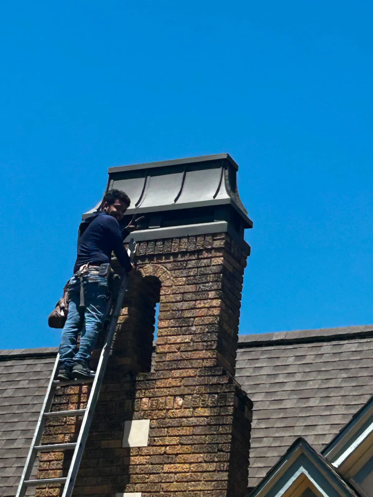 Master Pro technician working beside an exterior chimney on a residential roof